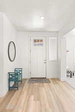 Foyer entrance with a textured ceiling and light wood finished floors