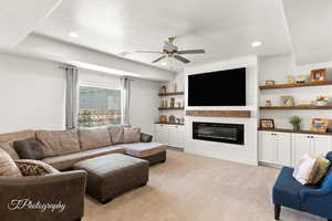 Living area with light colored carpet, a glass covered fireplace, a ceiling fan, recessed lighting, and a textured ceiling