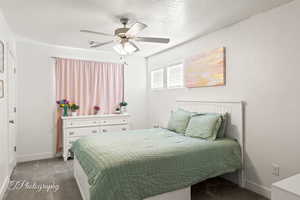 Bedroom featuring dark colored carpet, a ceiling fan, and a textured ceiling