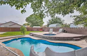 View of pool featuring a fenced backyard, a patio, a water slide, and an in-ground hot tub