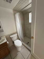 Bathroom with vanity, a stall shower, tile walls, tile patterned flooring, and a wainscoted wall