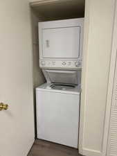 Washroom featuring dark wood-type flooring and stacked washer and clothes dryer