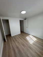 Unfurnished bedroom with a walk in closet and light wood finished floors
