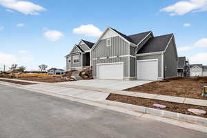 Craftsman house with board and batten siding, driveway, and a shingled roof