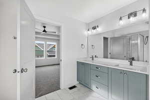 Bathroom with double vanity, light marble finish floors, a textured ceiling, a shower stall, and a ceiling fan