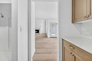 Kitchen with a premium fireplace, light stone countertops, light wood-type flooring, backsplash, and a textured ceiling