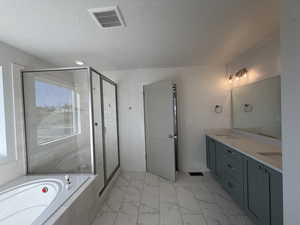 Bathroom featuring double vanity, a shower stall, a textured ceiling, a bath, and light marble finish floors