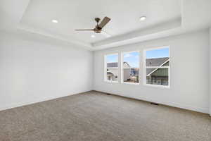 Unfurnished room featuring a tray ceiling, light colored carpet, a ceiling fan, and recessed lighting