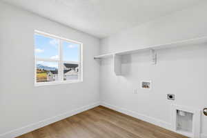 Washroom with electric dryer hookup, light wood-style floors, a textured ceiling, washer hookup, and a mountain view