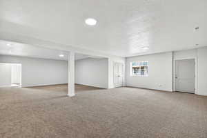 Basement featuring a textured ceiling, light carpet, and recessed lighting