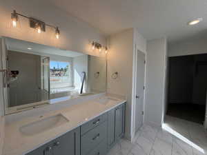 Full bath featuring double vanity, recessed lighting, a textured ceiling, light marble finish floors, and a bath