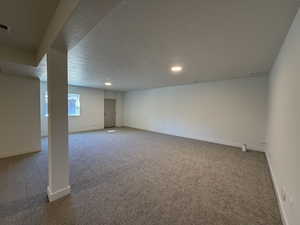 Basement with light colored carpet, a textured ceiling, and recessed lighting