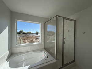 Bathroom featuring a garden tub, a shower stall, and a textured ceiling