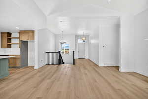 Unfurnished living room featuring a chandelier, light wood finished floors, recessed lighting, and vaulted ceiling