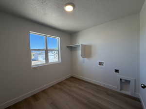 Laundry area featuring hookup for a washing machine, a textured ceiling, wood finished floors, and electric dryer hookup