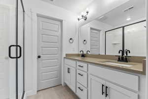 Full bath featuring double vanity, a textured ceiling, light tile patterned flooring, and a shower stall