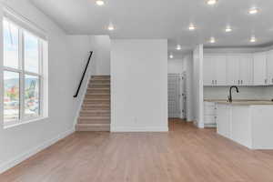 Unfurnished living room featuring light wood finished floors, recessed lighting, and stairway