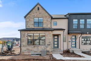 View of front of home with stone siding and a shingled roof