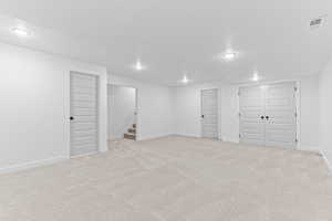 Finished below grade area featuring light colored carpet, stairway, a textured ceiling, and recessed lighting