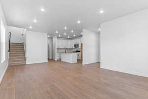 Unfurnished living room with stairway, light wood-style floors, and recessed lighting
