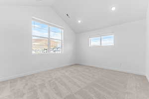 Empty room with vaulted ceiling, light colored carpet, and recessed lighting