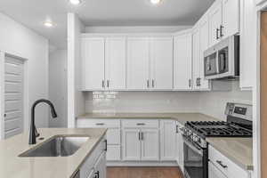 Kitchen with stainless steel appliances, white cabinetry, tasteful backsplash, light wood-style flooring, and recessed lighting
