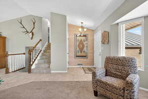 Living area with a chandelier, tile patterned floors, lofted ceiling, stairs, and carpet flooring