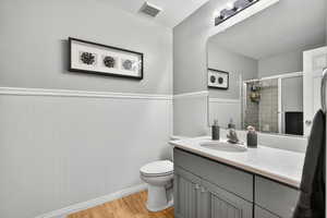 Bathroom with light wood-style floors, vanity, a stall shower, a wainscoted wall, and a textured ceiling