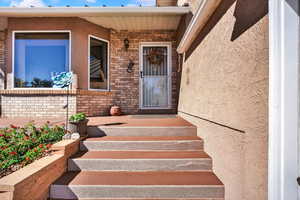 Doorway to property featuring brick siding and stucco siding