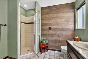 Bathroom featuring tile patterned floors, a stall shower, vanity, and wooden walls