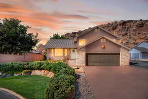View of front of property with brick siding, stucco siding, concrete driveway, and an attached garage