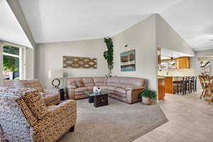 Living room featuring high vaulted ceiling and light tile patterned floors