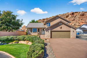 View of front of property with brick siding, a metal roof, driveway, a standing seam roof, and an attached garage