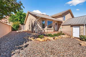 View of front of home featuring brick siding, a standing seam roof, a metal roof, stucco siding, and a fenced backyard