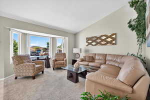 Living area with vaulted ceiling and light colored carpet