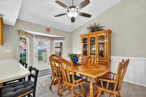 Tiled dining space featuring a ceiling fan and vaulted ceiling