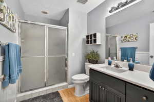 Bathroom featuring vanity, light wood-style floors, a textured ceiling, and a stall shower