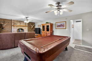 Rec room featuring a fireplace, a ceiling fan, a textured ceiling, billiards table, and carpet