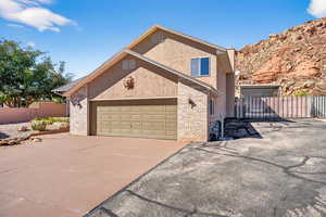 View of front of home featuring brick siding, driveway, stucco siding, and a garage