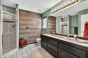 Bathroom with light tile patterned floors, double vanity, a stall shower, and a textured ceiling