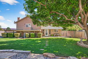 Rear view of property featuring a patio, a fenced backyard, stucco siding, a standing seam roof, and a chimney