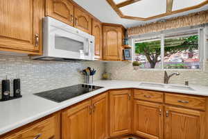 Kitchen featuring brown cabinets, backsplash, and white microwave