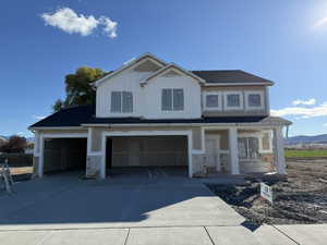 View of front of home with concrete driveway, a garage, board and batten siding, and stone siding