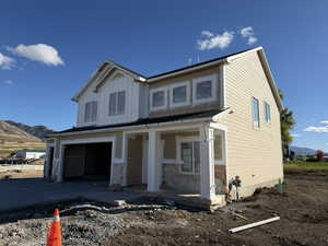 View of front of property featuring a mountain view, a garage, a porch, concrete driveway, and board and batten siding