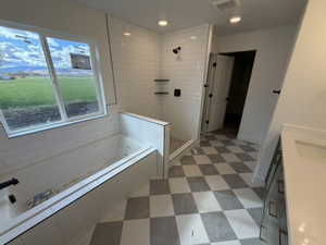 Bathroom with vanity, a bath, a stall shower, dark flooring, and recessed lighting
