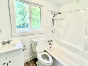 Bathroom with shower / bathtub combination, vanity, dark wood-style floors, and a textured wall