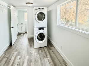 Laundry room featuring stacked washing machine and dryer and light wood finished floors