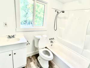 Bathroom with vanity, wood finished floors, and shower / washtub combination