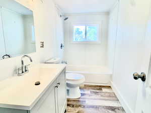 Full bath featuring vanity, light wood finished floors, tub / shower combination, and a textured wall
