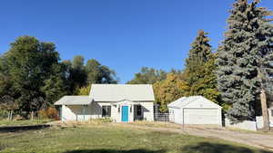 View of front facade featuring a detached garage, an outdoor structure, and a metal roof